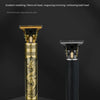 A close-up view of a gold and black electric clipper with an engraved oil head scissor design.