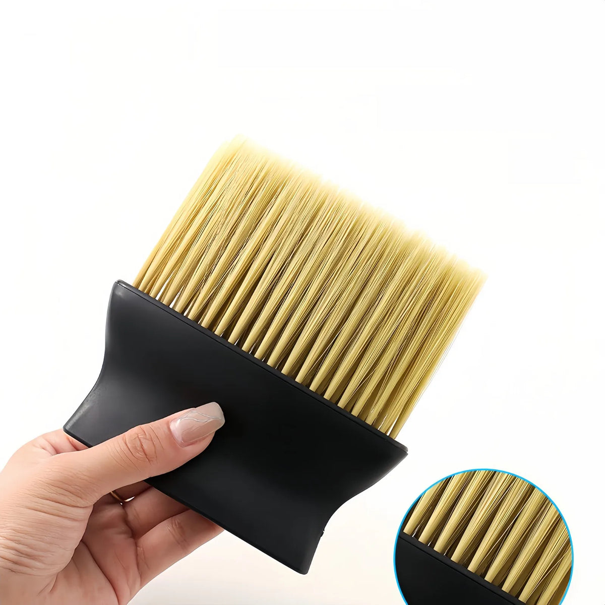 Une main tient un tablier de coiffure professionnel noir et un peigne de coiffure avec des poils dorés.