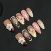Colección de 10 uñas postizas talladas a mano con diseño de pétalo almendra rosa y blanco y acentos dorados.