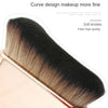 A close-up of a black and tan makeup brush with soft bristles shown in a studio setting.