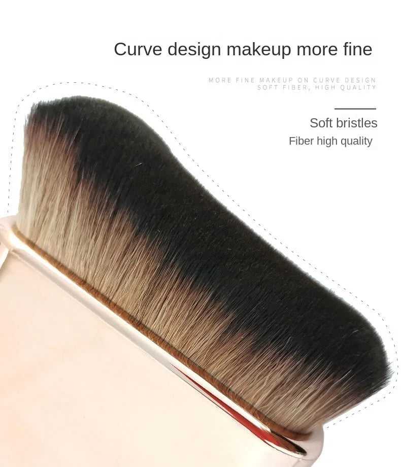 A close-up of a black and tan makeup brush with soft bristles shown in a studio setting.