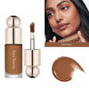 A tube of Rare Beauty Serene liquid bronzer contour foundation stick with a doe foot applicator and a swatch of the product.
