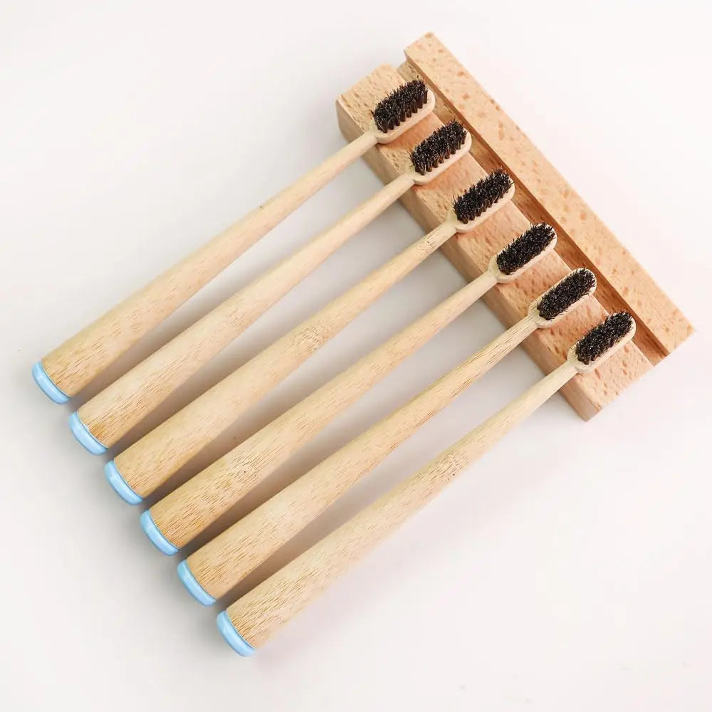 Un pack de six brosses à dents biodégradables à poils de cheval et manches en bambou, arrangées sur un plateau en bois.