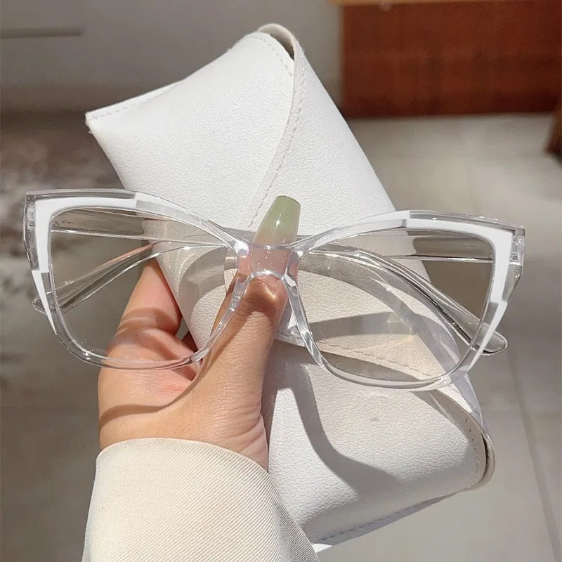 Une main tient une paire de lunettes de lecture élégantes à monture chat-œil claires avec des branches vert clair et des extr