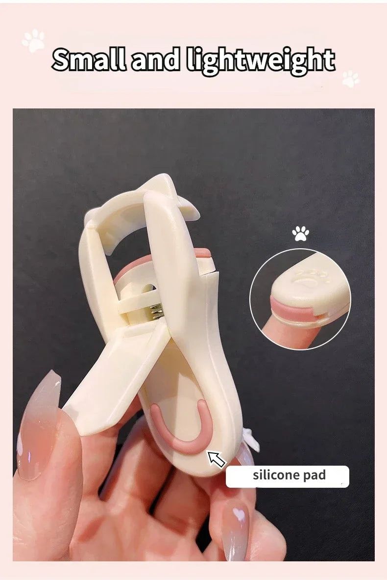 Une main tient un petit recourbe-cils en silicone pour chats, de couleur rose pâle.