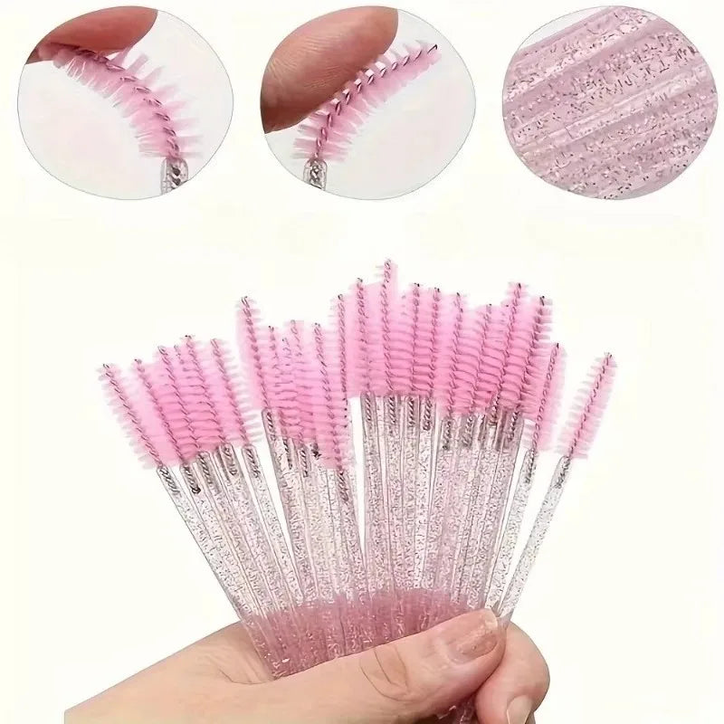 A hand holds a bundle of pink and black disposable eyelash and eyebrow makeup brushes.