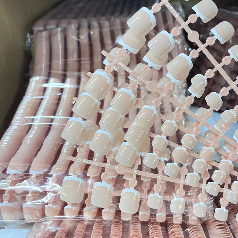 A collection of pink French press on toenails for summer decor displayed in clear packaging.