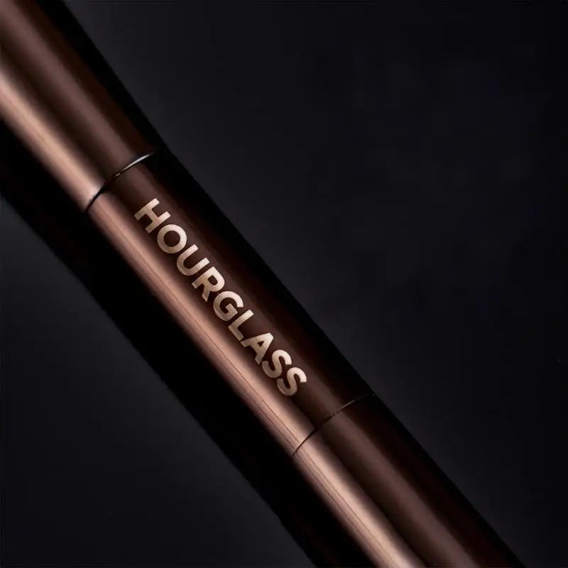 A close-up of a brown makeup brush with the word HOURGLASS engraved on the handle.