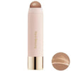 A tube of liquid bronzer contour foundation stick with a pink body and gold cap.