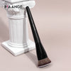 A black flat kabuki foundation brush resting on a white classical column base.