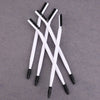 A set of white dual-ended eyelash curlers and brow brushes arranged diagonally on a gray surface.