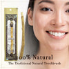 A close-up of a woman smiling, holding a traditional wooden miswak toothbrush packaged in a decorative pouch.