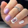 A hand displays a set of blue floral press-on false nails on a finger, with a silver ring visible.