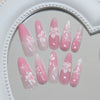A set of pink cat eye false nails featuring 3D floral and butterfly designs displayed in a circular mirror frame.