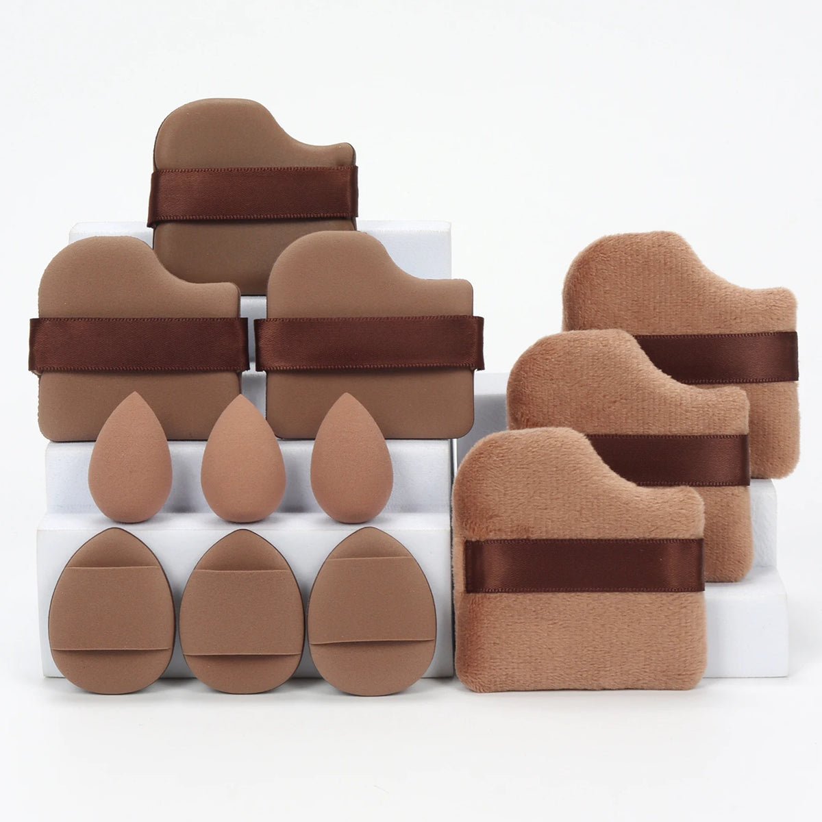 A set of twelve brown makeup sponges with dark brown bands, arranged in a white box.
