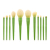 A set of ten professional makeup brushes with green handles and light yellow bristles arranged in a row.