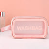 A pink cosmetic storage bag with a pink strap is displayed on a white surface next to a glass bottle.