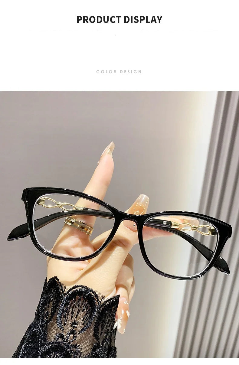 Lunettes de lecture à monture de chat noir avec accents dorés tenues par une main sur fond clair.