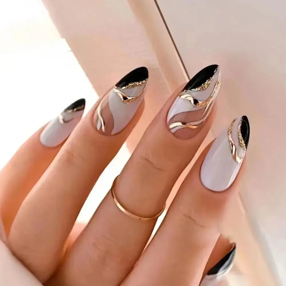 A hand displaying press-on false nails with a French wavy design featuring white and gold accents.
