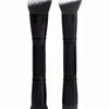 A pair of black makeup foundation brushes with silver ferrules and fluffy gray and white bristles.