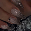 Close-up of a hand displaying pink flower almond press on nails with a glitter finish.
