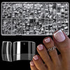 A clear plastic container filled with medium clear almond acrylic nail tips and a black nail file.