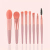 A set of pink makeup brushes and a sponge displayed vertically on a light background.