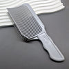 A gray professional barber hair cutting comb with a handle is shown resting on a dark surface next to a white comb.