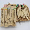 A collection of 100 eco-friendly bamboo toothbrushes in various colors and sizes displayed on a wooden tray.