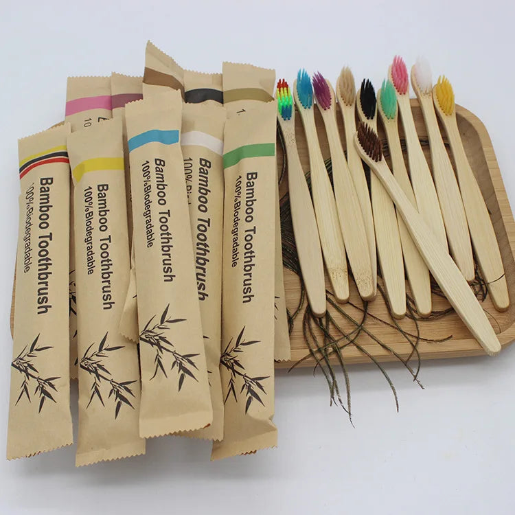 A collection of 100 eco-friendly bamboo toothbrushes in various colors and sizes displayed on a wooden tray.