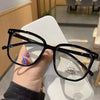 Una persona sostiene unas gafas cuadradas negras vintage anti-luz azul contra un fondo blanco.