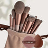 A collection of 15 makeup brushes in rose gold and nude tones displayed in a beige pouch.