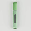 A slender, cylindrical portable refillable perfume bottle in a light green color with a silver band and a black inner section