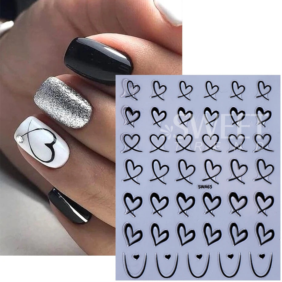 Une main présente divers autocollants de cœurs d'amour 3D en noir et argent sur les ongles.