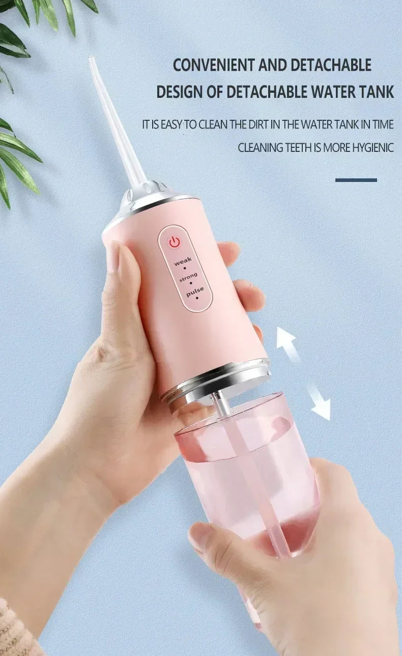 A hand holds a pink dental water flosser device, demonstrating its convenient and detachable design for cleaning teeth.
