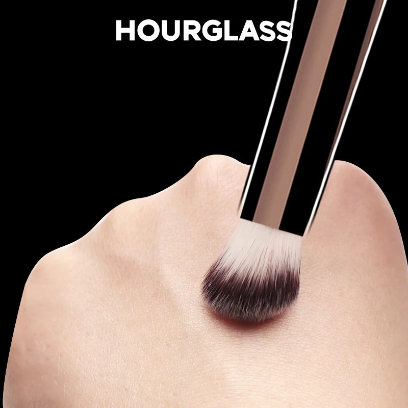 Gros plan d'une brosse de correcteur Hourglass en fibre douce tenue par une main.