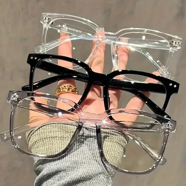 Una mano sostiene unas gafas cuadradas vintage transparentes anti-luz azul y unas gafas negras.