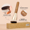 A golden aluminum tube foundation brush with a wooden handle and synthetic hair bristles shown next to its packaging box.
