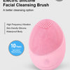 A pink electric silicone facial cleansing brush with a textured head and power switch.