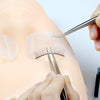 A hand uses tweezers to apply silicone eyelash extensions on a practice mannequin head.