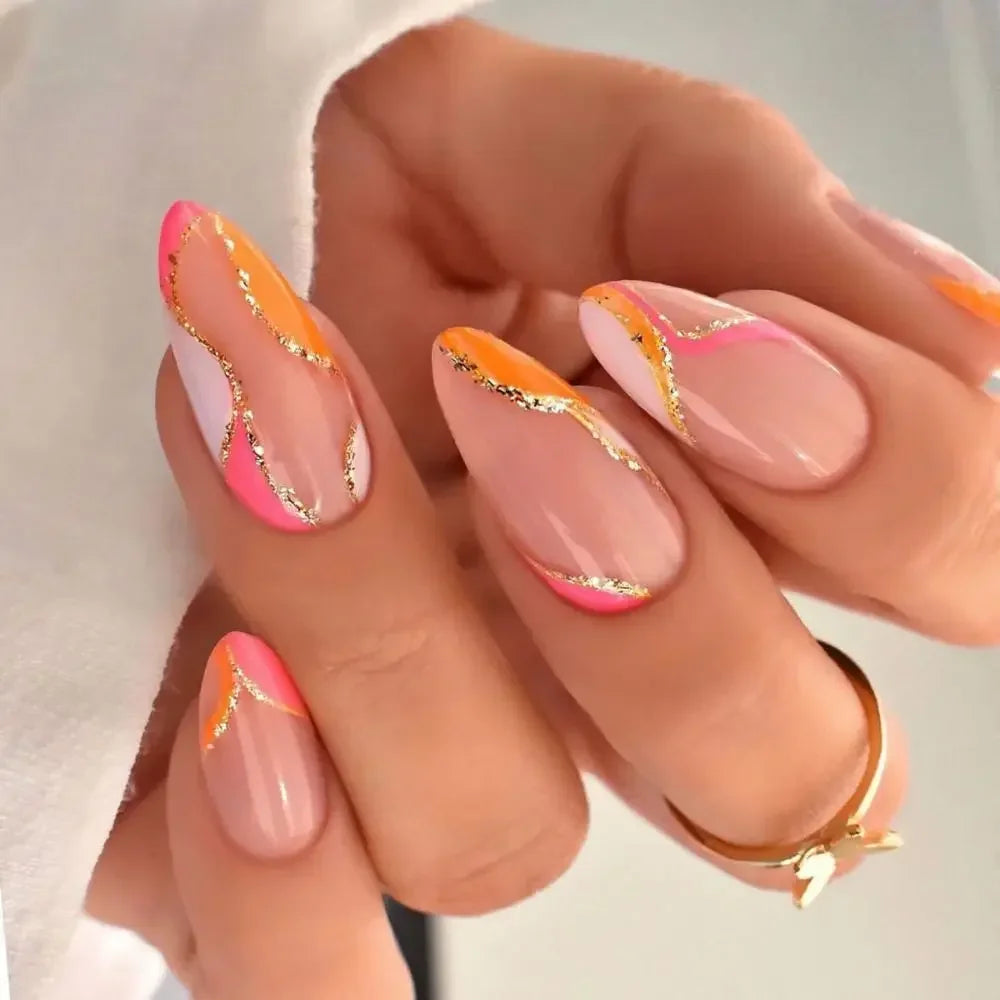 A hand displaying press-on false nails with a French wavy design featuring pink and gold glitter accents.