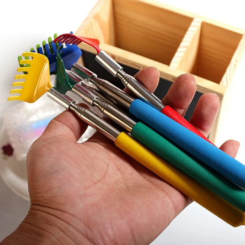 A hand holds a set of colorful stainless steel telescopic back scratchers inside a wooden box.