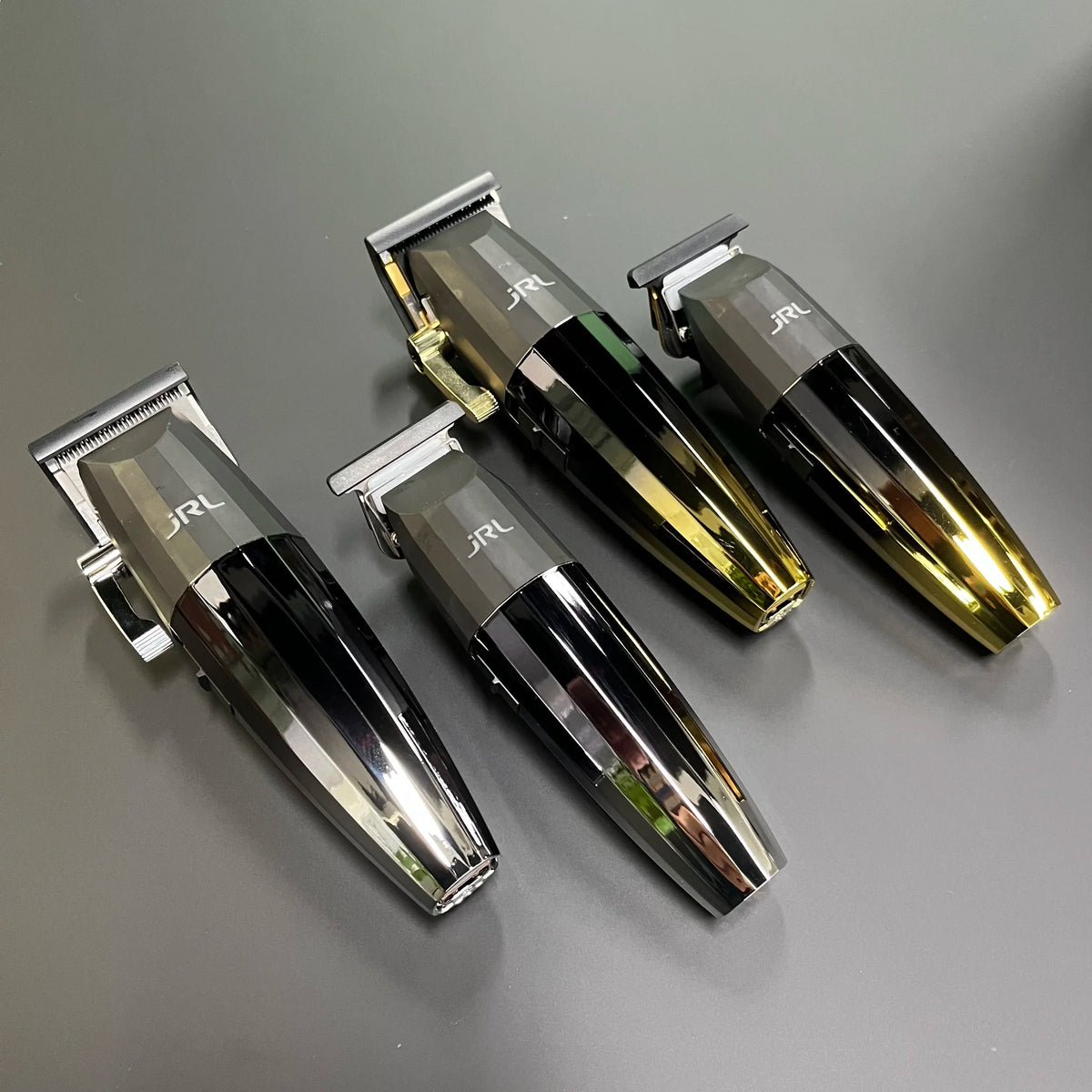 Drei professionelle rotierende Haarschneidemaschinen mit silbernen und goldenen Akzenten auf grauer Oberfläche.