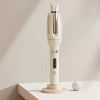 A white automatic ceramic hair curler with negative ions is displayed on a light surface.