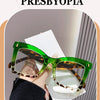 A pair of green-framed reading glasses with brown tortoiseshell lenses shown on a person's hand.