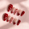 A set of red and pink Y2K almond press-on nails featuring a white heart design on each nail.