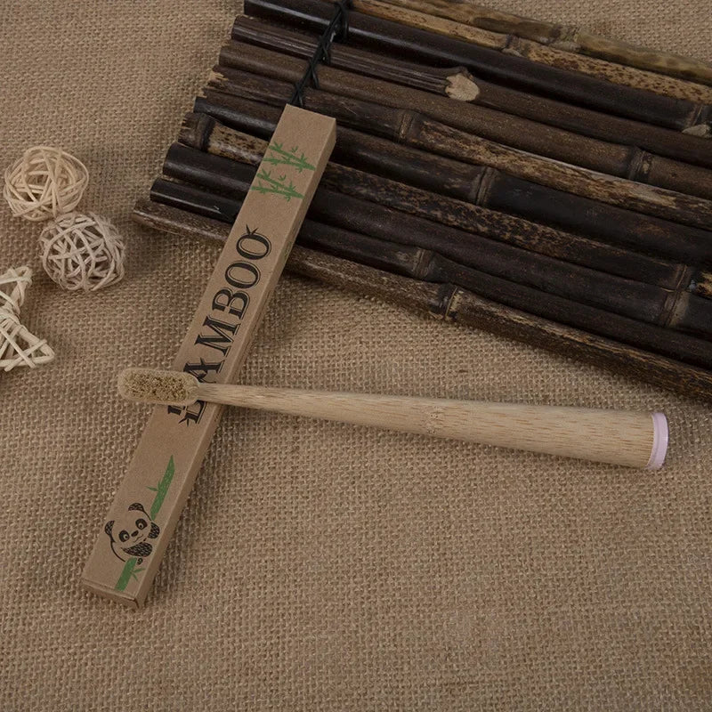 A wooden bamboo toothbrush set with a handle and bristles is displayed on burlap fabric.