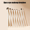 A set of eight white eye makeup brushes displayed in a row against a light background.