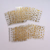 A collection of gold star nail art stickers and 3D decals for acrylic nails spread across a white surface.
