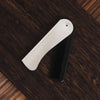 A silver foldable anti-static steel comb lying on a dark wooden surface.